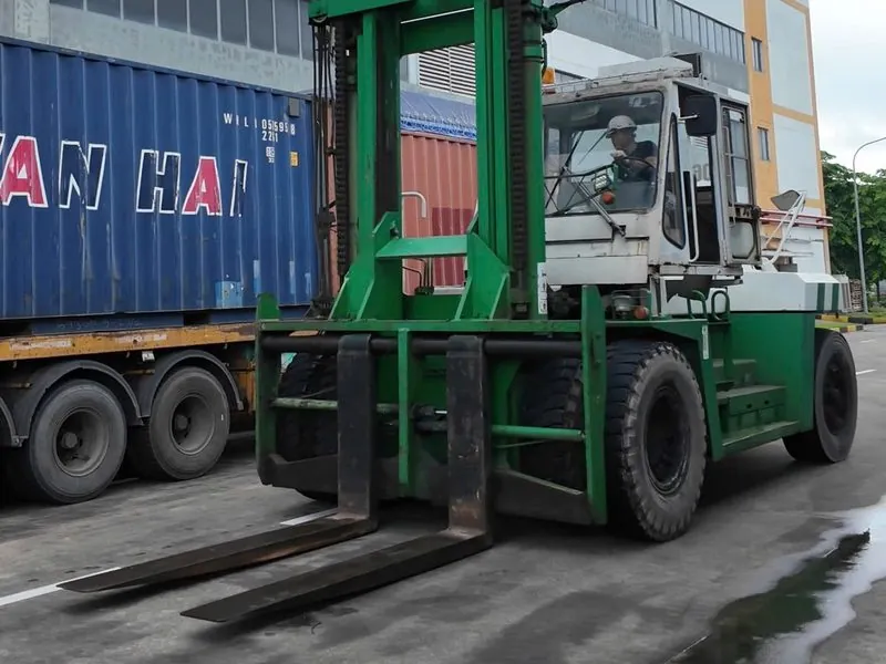 Xe nâng hạng nặng cạnh container tại nhà máy
